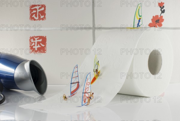 Indoor surfing by little world miniatures on toilet paper with hairdryer as background for the wind
