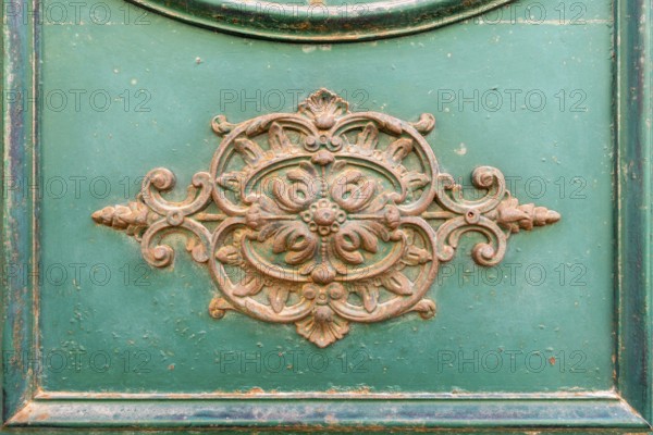 An image of a rusty ornamental decoration at a green door in Italy