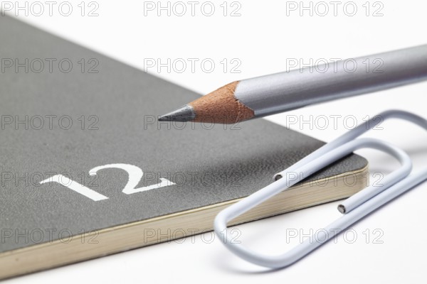 Organizer for the month of December, silver pencil and white paperclip on the white table