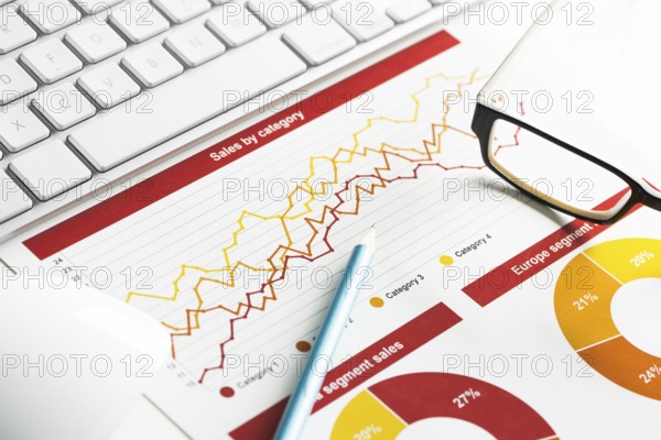Business workplace with keyboard mouse and papers with graphs and diagrams