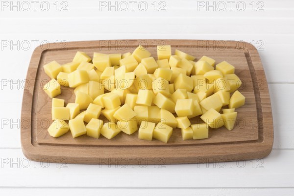 Food, Wooden board with fresh diced potatoes on a light gray background. Stage of cooking vegetable stew