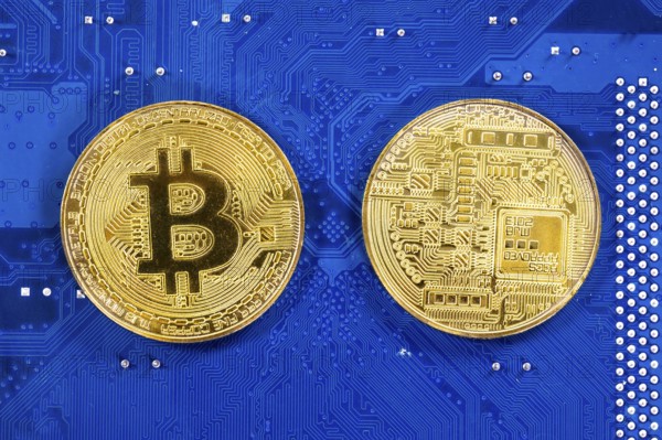 Virtual cryptocurrency money Bitcoin golden coins on a computer printed circuit board PCB. The future of money. Computational equipment. Blue mother board. Shot directly from above