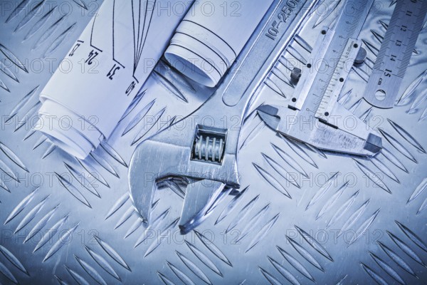 Blueprints vernier scale caliper monkey spanner on channeled metal background construction concept