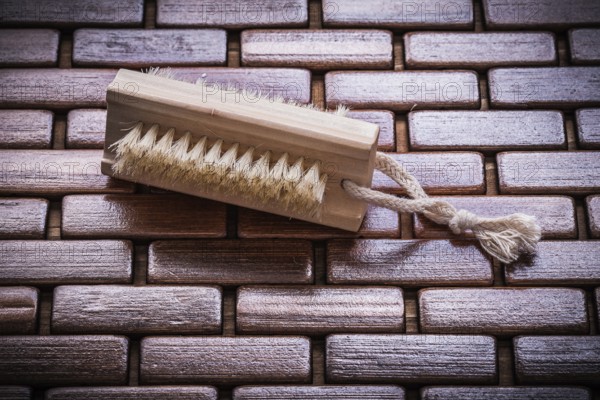 Wood scrubbing brush on textured wooden matting top view healthcare concept