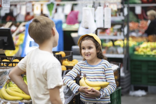 Kids little cute girl and teenager boy shopping for fresh organic fruits bananas and vegetables in supermarket