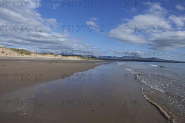 Beach and dunes with calm sea, in the background the mountains of Snowdonia National Park, Ynys Llanddwyn, Newborough, Anglesey, Wales, United Kingdom
