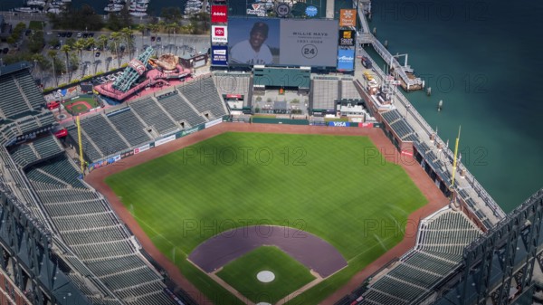The San Francisco Giants honor Willie Mays, who recently passed away, with a tribute on the centerfield Jumbotron at Oracle Park. The aerial view captures the stadium's beauty against the backdrop of San Francisco Bay