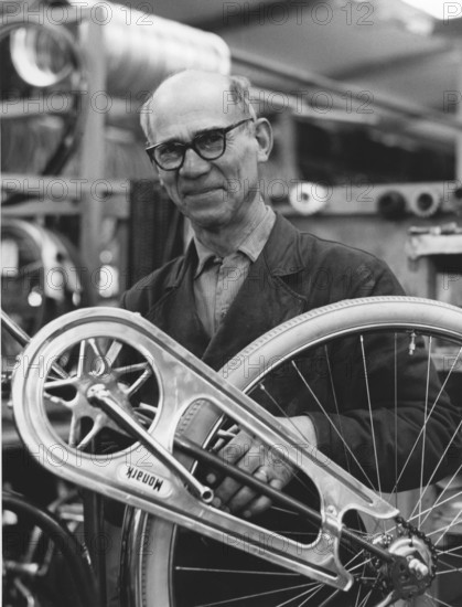 Factory in the 1950s. A worker at the bicycle and motorcycle company Monark in Sweden. He is standing by an bicycle that is nearly finished in production. Sweden 1958