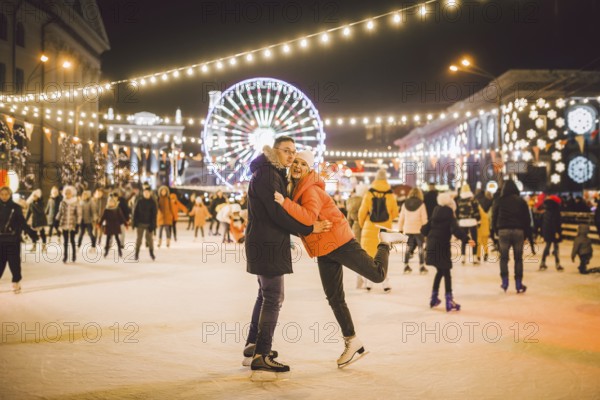 Couple hugging in Saint Valentine's Day. Young romantic couple having fun outdoors in winter. St Valentines Day at city ice rink. New Year holidays. active date ice skating on ice arena on Christmas