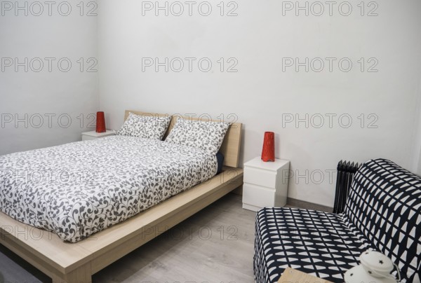 Small cozy bedroom interior furnished with comfortable soft bed and chair in contemporary apartment
