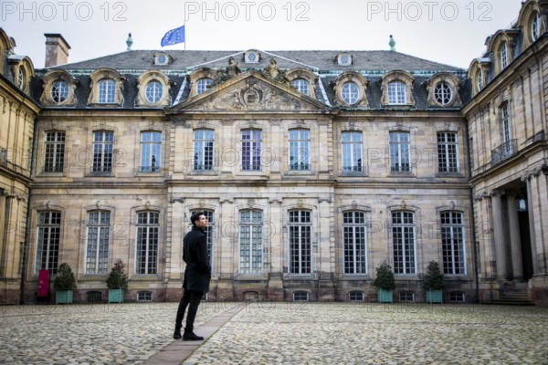 Attractive young man standing in courtyard of historic building in Strasbourg, France