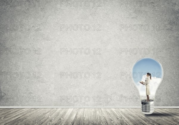 Businesswoman inside of light bulb in empty concrete room