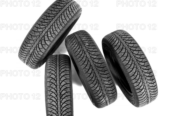 Isolated on white, four new black rubber automobile tires with protector standing