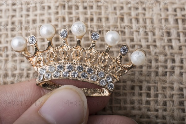 Golden color crown model with pearls on brown background