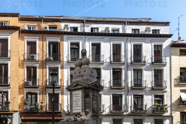 Madrid, Spain, November 1, 2020: Old residential building with iron balconies in the downtown of Madrid. Sculpture to Fernando VII King. Toledo Street