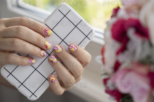 Stylish summer colorful nails female manicured hands holding mobile phone. Closeup of manicured nails of woman hand. Summer style of nail design concept. Beauty treatment