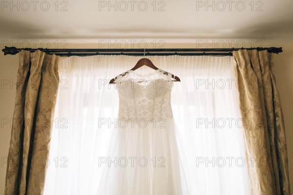 The bride's dress hangs on the cornice on the window