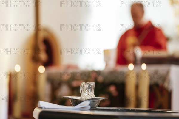 Holy water during baptism catholic mass with priest in the background