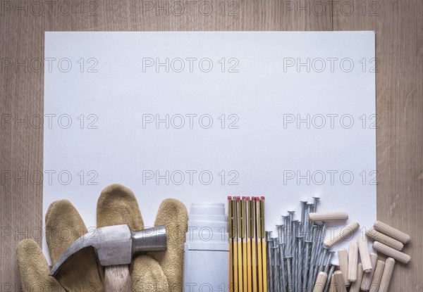 Wooden meter blueprints sheet of paper nails claw hammer fluted dowels and leather safety gloves on wood board copy space construction concept