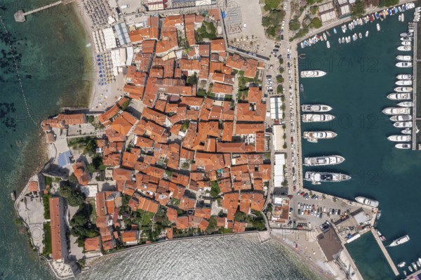 Aerial top view of walled old town of Budva city. Pier with moored yachts and boats. Adriatic sea, Montenegro
