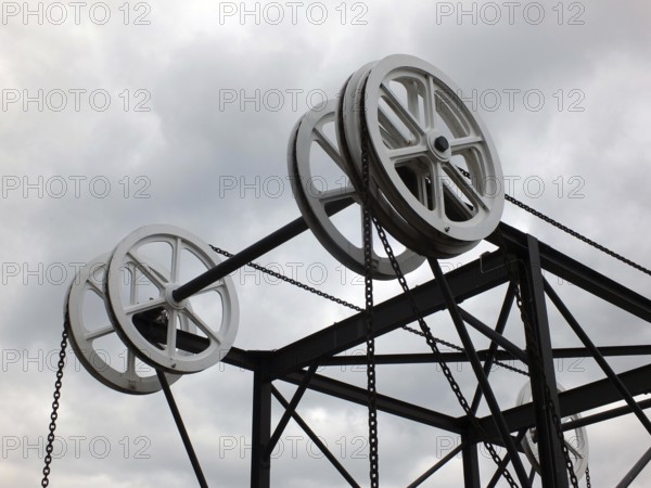 Wheels and pulleys on the historic canal chain bridge in Huddersfield West Yorkshire against grey clouds