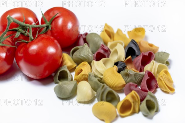Coloured Italian snail pasta made from durum wheat semolina with red vine tomatoes against a white background