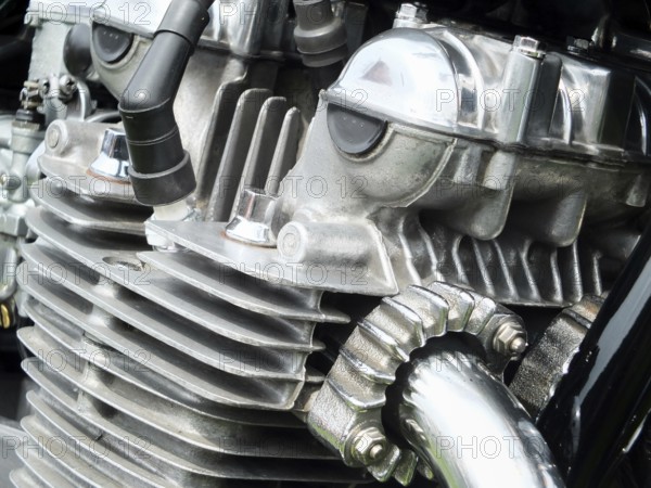 Close up detail of the engine of an old vintage motorcycle with black frame and shiny chrome exhaust pipes