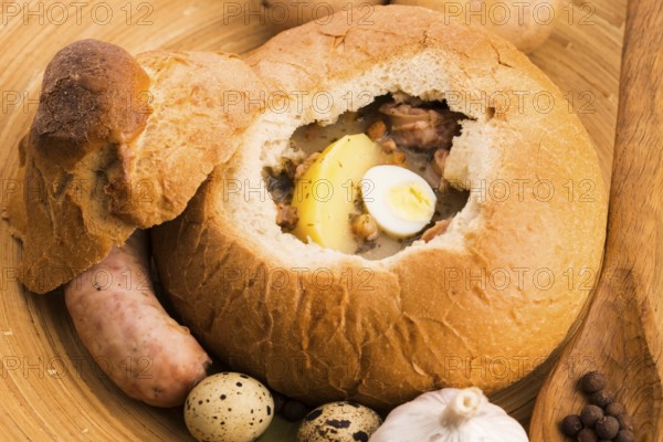 Traditional white borscht (zurek) with sausage, egg and mushrooms in bread as a dish
