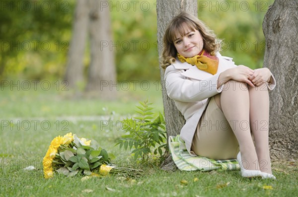 Young cute girl with a bouquet of yellow roses in autumn cool weather