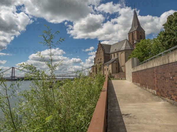 Walkway along a church, in the background a bridge and clouds in the blue sky, emmerich, lower rhine, germany