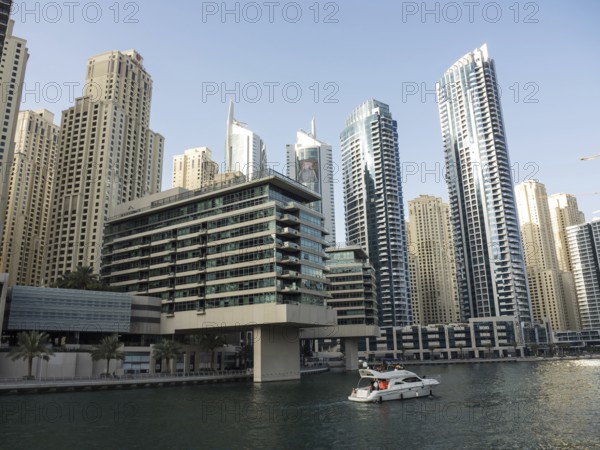 Modern skyscrapers on the riverbank with a boat on the water, impressive skyline of a modern city with spectacular skyscrapers, dubai, arab emirates