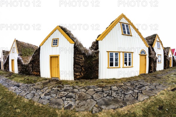 Traditional houses with grass-covered roofs and white and yellow facades, Iceland
