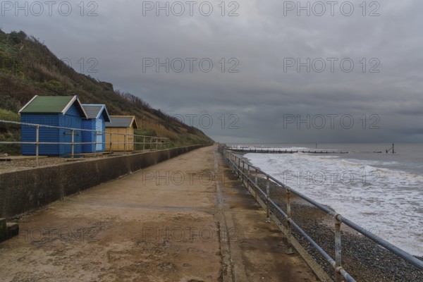 Dark clouds over the beach huts on Overstrand Beach, Norfolk, England, UK