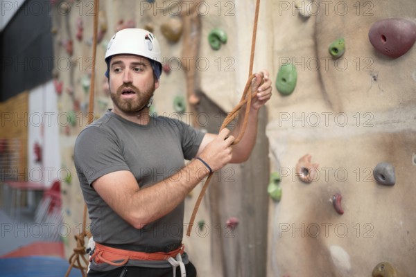 Man climber preparing to climb artificial indoor climbing wall