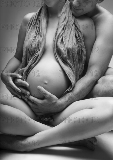 Young man and pregnant woman in studio in lingerie