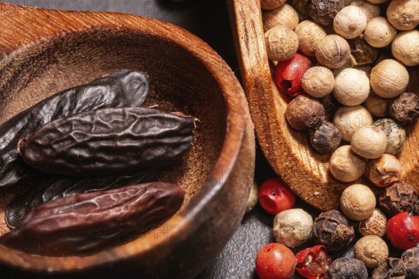Tonka Beans and different kind of Peppercorns in a wooden spoon