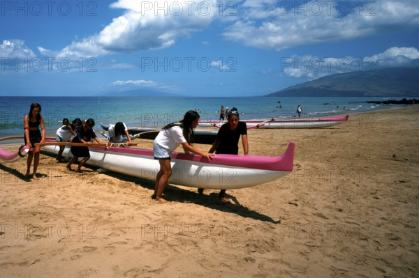 Kihei beach, an outrigger boat is pushed ashore by schoolgirls after physical education class, Maui Island, Hawaii, USA