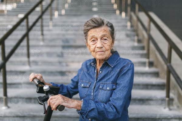 90 year old woman with grey hair, wrinkles, progressive and active uses modern electric transport scooter. Lady pensioner use eco friendly city vehicle. Senior female using urban personal transport