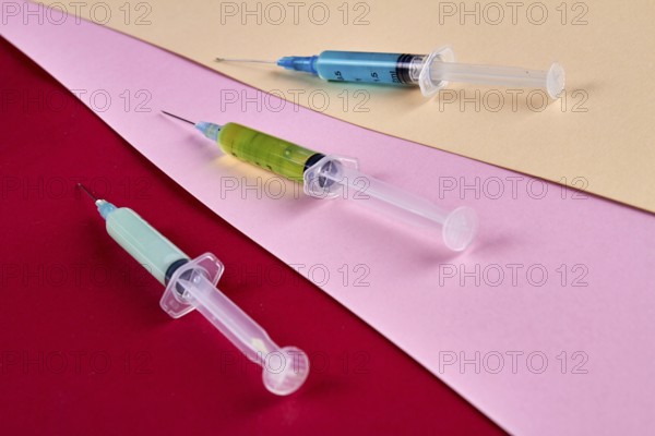 Close-up three syringes filled with multicolored medicine liquids. Drugs addiction and injections concept