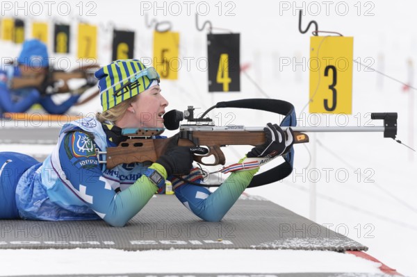 Sportswoman biathlete Legostaeva Anastasia rifle shooting in prone position. Biathlete in shooting range. Open regional junior biathlon competitions East Cup. Kamchatka, Russian Far East, Apr 12, 2019