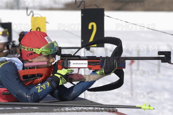 Sportswoman biathlete aiming, rifle shooting, reloading prone position. Biathlete Polina Yegorova Kazakhstan in shooting range. Junior biathlon competitions East Cup. Kamchatka, Russia, Apr 14, 2019