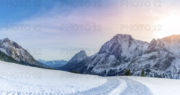 Winter landscape with a road made by a snowmobile, its traces through the layer of snow, in the Austrian Alps mountains, on a sunny day of December