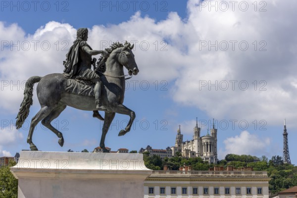 Large equestrian statue of Louis XIV on a pedestal on Place Bellecour and in the background Basilique Notre-Dame de Fourvière (Notre-Dame de Fourvière), Lyon, Auvergne-Rhône-Alpes, Métropole de Lyon, France