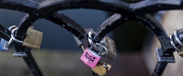Colorful padlocks on a metal fence, including a pink love-themed lock in the London Borough of Camden, Greater London, United Kingdom