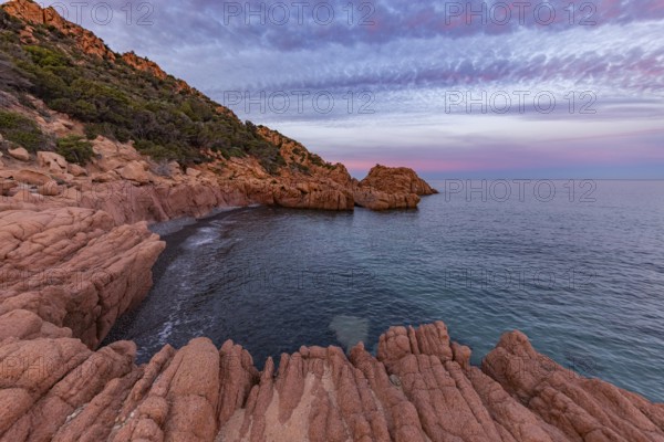 Large red rocks at the edge of the sea under a cloudy evening sky, Spiaggia di Cala E'Luas, Ogliastra, Sardinia, Italy
