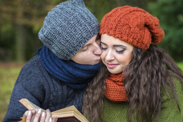 Loving couple reads a book in the autumn garden