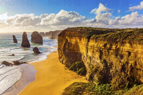 Rocks of the Twelve Apostles at sunset. Powerful Pacific surf breaks down on the shore. Grandiose coast of Australia. The concept of exotic, active and photo-tourism