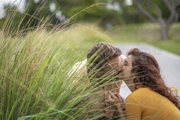 Couple secretly kissing behind a bush in a park