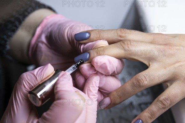 Close-up view of a nail technician applying polish to fingernails