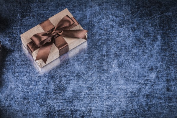 Present box with bow on scratched metallic background holidays concept